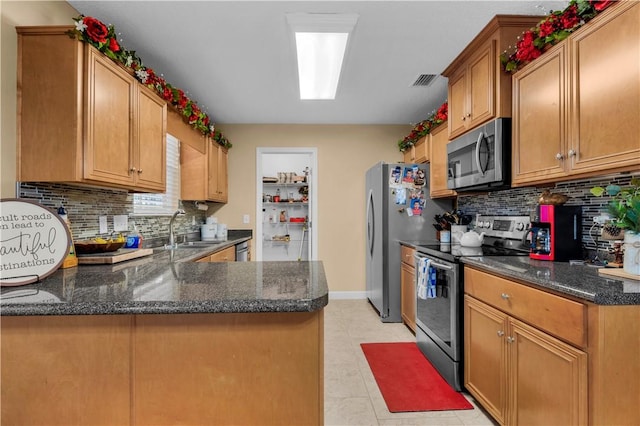 kitchen featuring stainless steel appliances, sink, backsplash, and kitchen peninsula