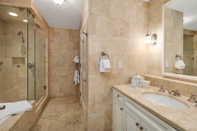 bathroom with vanity, a shower with door, and tile walls