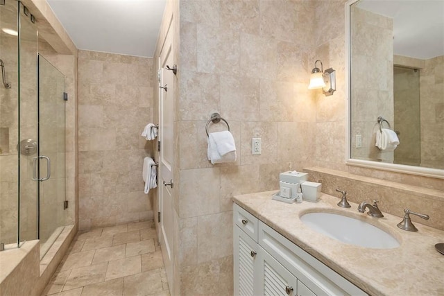 bathroom with vanity, a shower with shower door, and tile walls