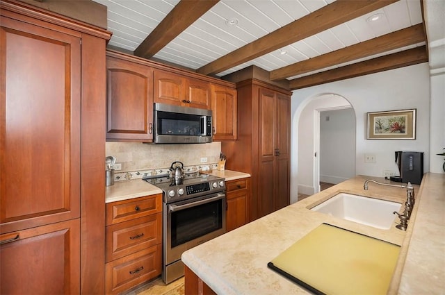 kitchen featuring backsplash, sink, beamed ceiling, and stainless steel appliances