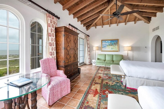 bedroom with beam ceiling, multiple windows, and high vaulted ceiling