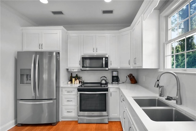 103 Bellrain Ln, Saint Simons Island, GA 31522 - kitchen with appliances with stainless steel finishes, healthy amount of natural light, white cabinets, light countertops, and ornamental molding