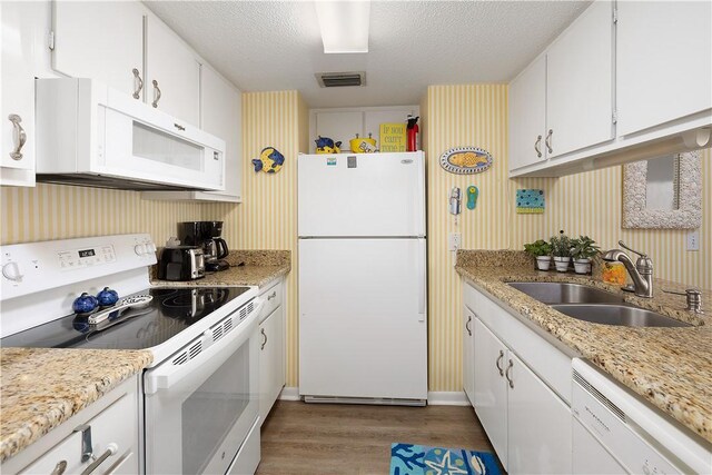 kitchen with a textured ceiling, white appliances, sink, light hardwood / wood-style floors, and white cabinetry