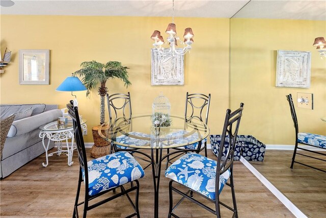 dining space with hardwood / wood-style floors and a notable chandelier