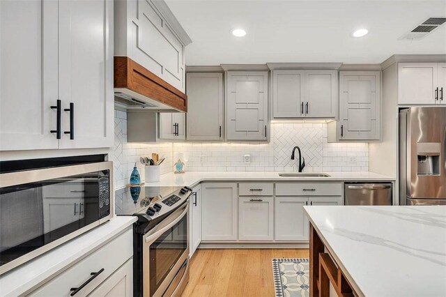 kitchen with light wood finished floors, a fireplace, appliances with stainless steel finishes, and backsplash