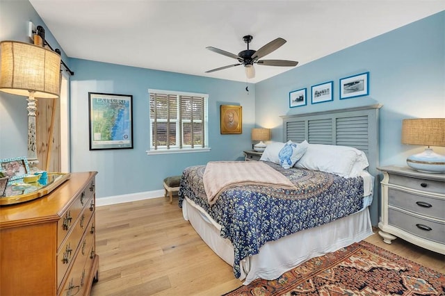 bedroom featuring a ceiling fan, light wood-style flooring, baseboards, and a barn door