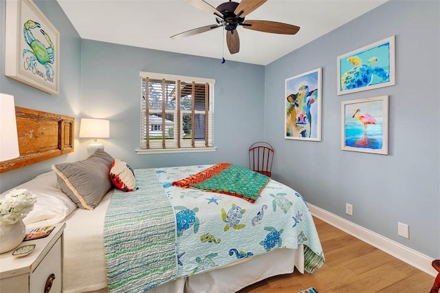 bedroom with ceiling fan, wood finished floors, and baseboards