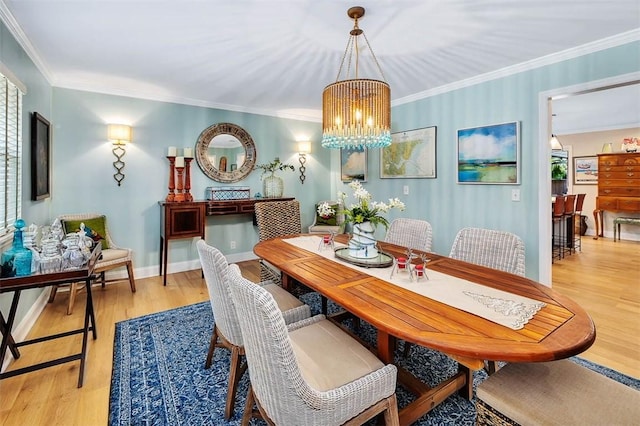 dining area with ornamental molding, light wood-type flooring, a notable chandelier, and baseboards