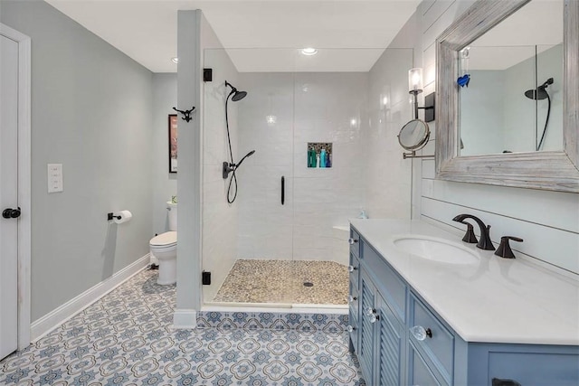 bathroom with toilet, a shower stall, baseboards, and vanity