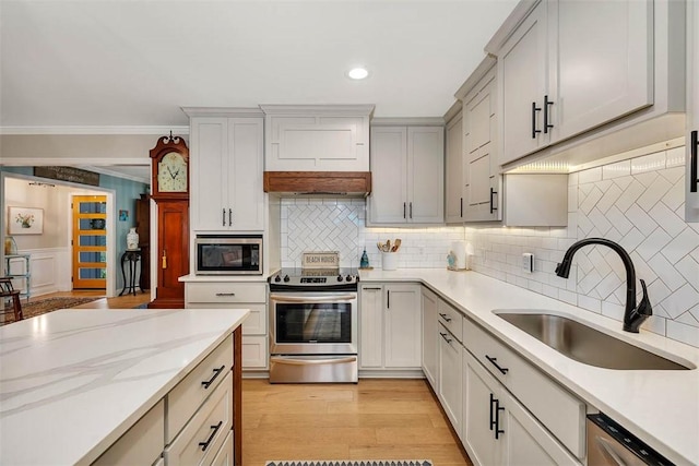 kitchen with stainless steel appliances, a sink, ornamental molding, light wood-type flooring, and decorative backsplash