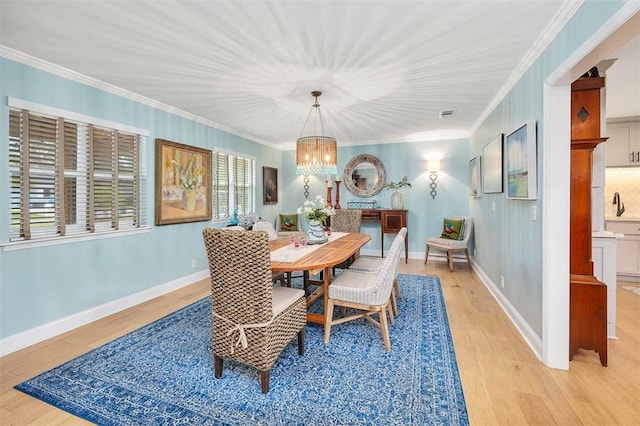 dining space featuring light wood finished floors, ornamental molding, a chandelier, and baseboards