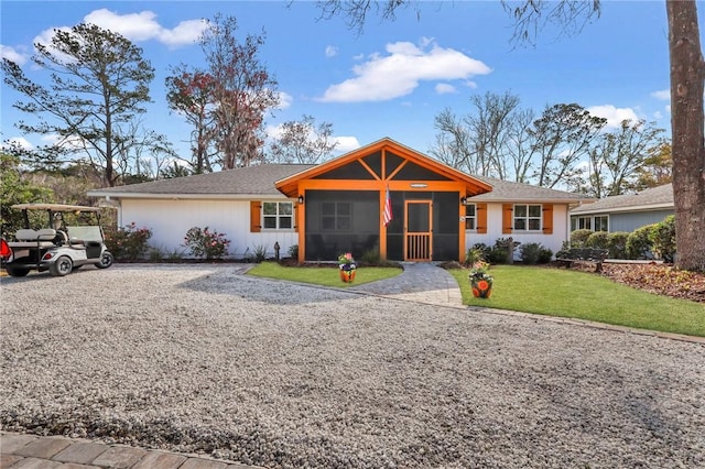 ranch-style home with driveway, a front yard, and a sunroom