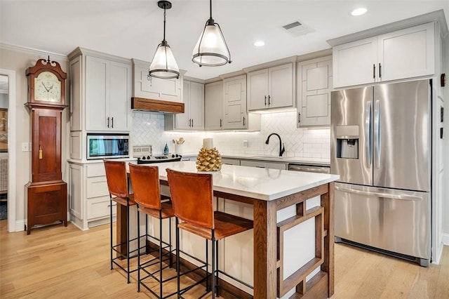 kitchen featuring light wood-style flooring, visible vents, stainless steel appliances, and a sink