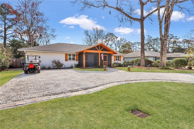 single story home featuring driveway, a front lawn, fence, and a sunroom