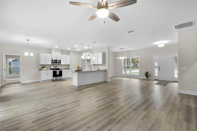 unfurnished living room featuring ceiling fan with notable chandelier, sink, and light hardwood / wood-style flooring