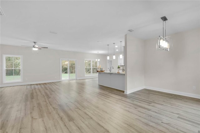 unfurnished living room with a wealth of natural light, ceiling fan, and light wood-type flooring