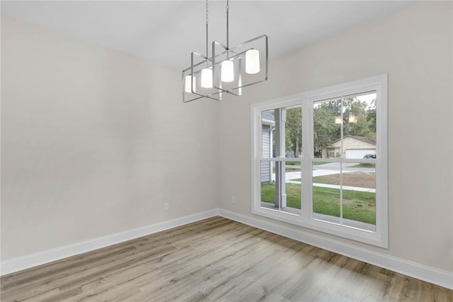 unfurnished dining area with a chandelier, light hardwood / wood-style floors, and a healthy amount of sunlight