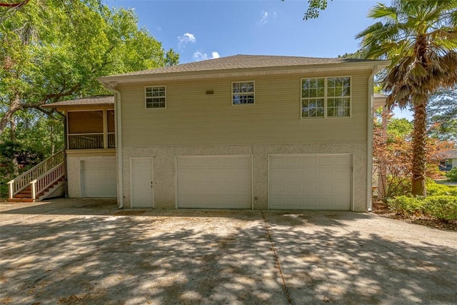 212 Stillwater Dr, Brunswick, GA 31525 - exterior space featuring driveway, an attached garage, stucco siding, roof with shingles, and stairs