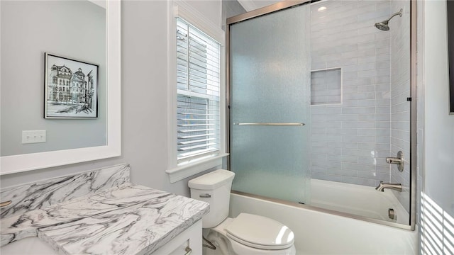 full bathroom with shower / bath combination with glass door, plenty of natural light, vanity, and toilet