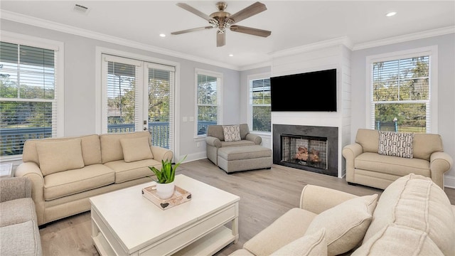 living room with light wood-type flooring, ceiling fan, and ornamental molding