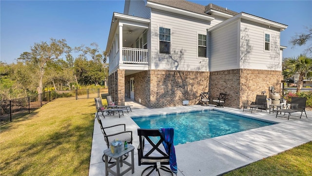 rear view of property with a yard, a fenced in pool, ceiling fan, and a patio area