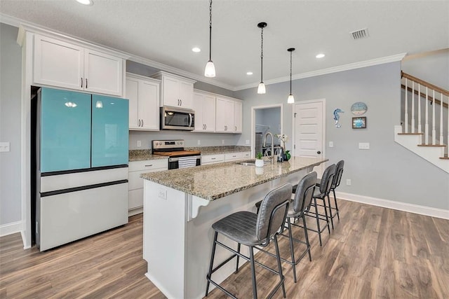 69 Allie Loop, Brunswick, GA 31525 - kitchen with appliances with stainless steel finishes, crown molding, wood finished floors, white cabinets, and an island with sink