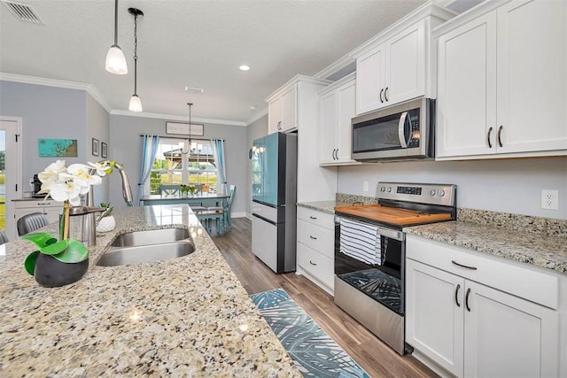 69 Allie Loop, Brunswick, GA 31525 - kitchen with stainless steel appliances, ornamental molding, white cabinets, dark wood finished floors, and hanging light fixtures