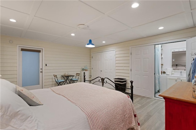 bedroom with recessed lighting, multiple closets, wood finished floors, and wooden walls