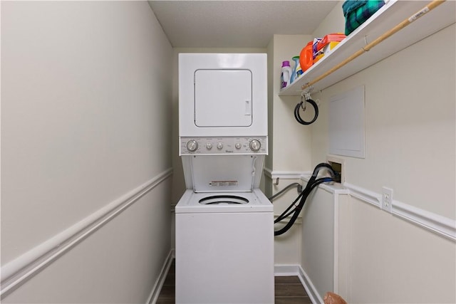 laundry area featuring stacked washing maching and dryer, baseboards, laundry area, and wood finished floors