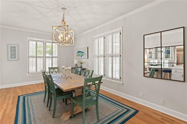 dining room featuring an inviting chandelier, baseboards, crown molding, and wood finished floors