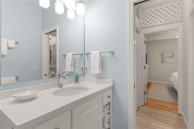 ensuite bathroom featuring baseboards, wood finished floors, ensuite bathroom, and vanity