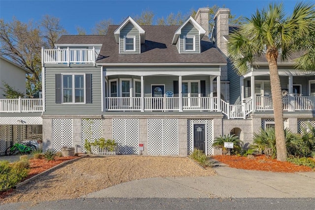 view of front of house featuring roof with shingles, a chimney, a porch, and a balcony