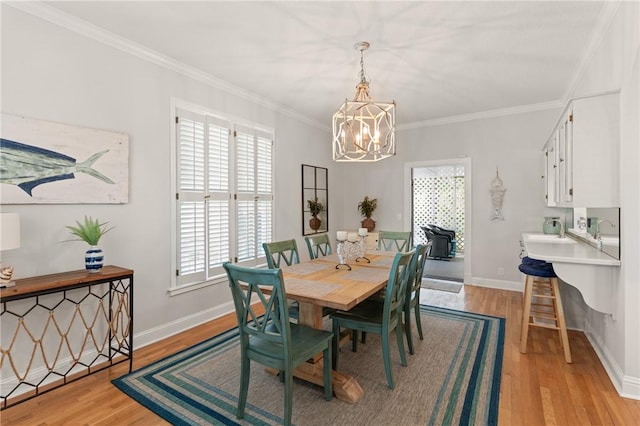 dining area featuring a notable chandelier, ornamental molding, a healthy amount of sunlight, and light wood-style flooring