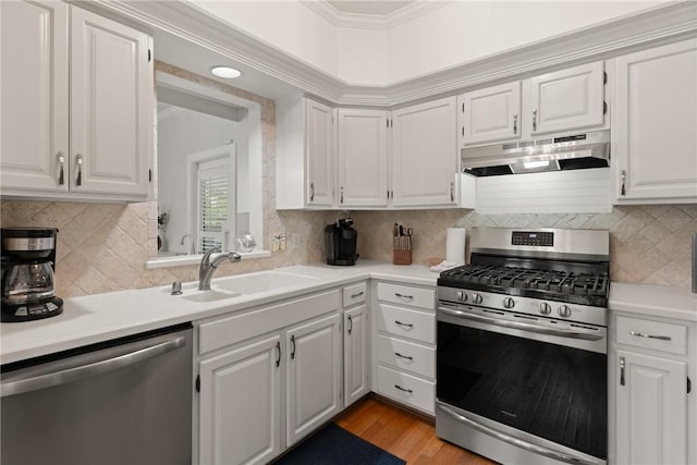kitchen featuring white cabinets, a sink, light countertops, stainless steel appliances, and under cabinet range hood