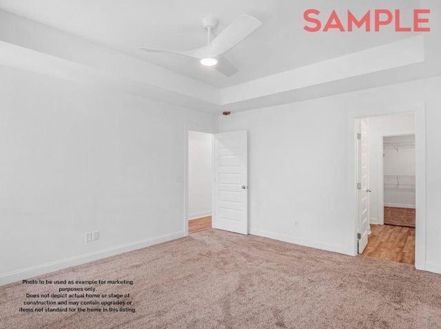 unfurnished bedroom featuring light carpet, a closet, a spacious closet, and ceiling fan