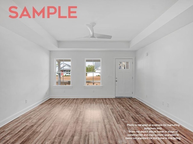 empty room featuring hardwood / wood-style floors, ceiling fan, and a raised ceiling