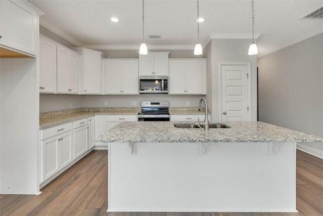 kitchen with white cabinets, an island with sink, stainless steel appliances, and decorative light fixtures