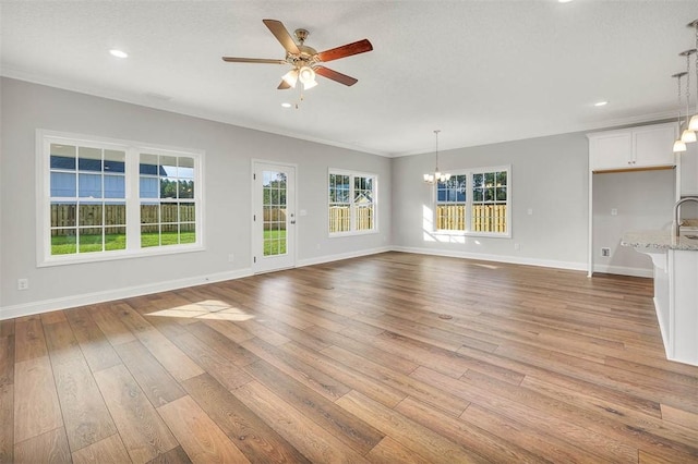 unfurnished living room featuring ceiling fan with notable chandelier, sink, ornamental molding, a textured ceiling, and light hardwood / wood-style floors