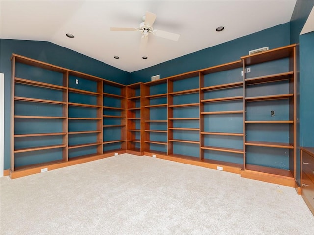 carpeted empty room featuring visible vents, a ceiling fan, and vaulted ceiling