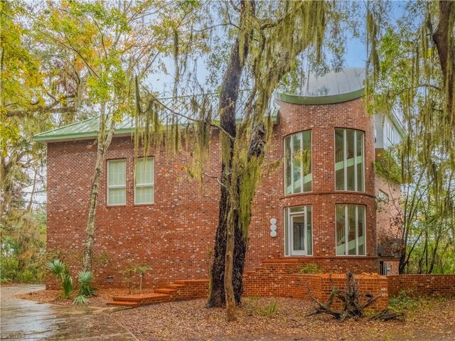 view of home's exterior featuring brick siding and metal roof