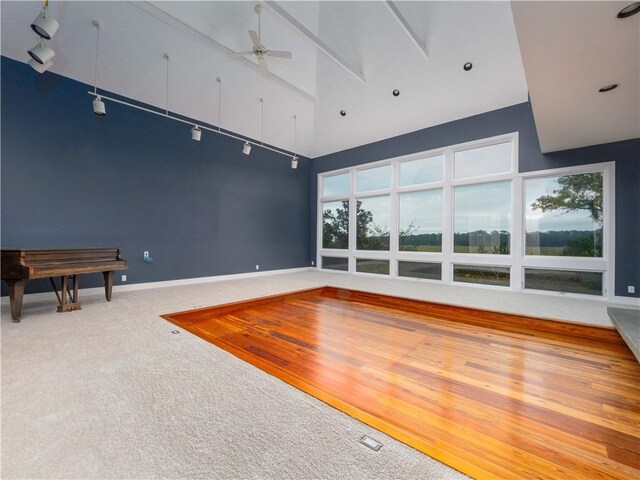 interior space featuring baseboards, carpet floors, a high ceiling, and a ceiling fan