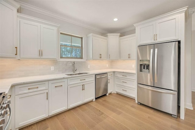 kitchen with stainless steel appliances, ornamental molding, sink, and white cabinets