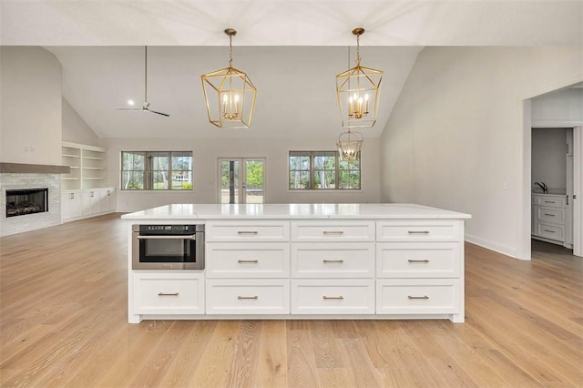 kitchen featuring white cabinetry, decorative light fixtures, light hardwood / wood-style floors, and oven