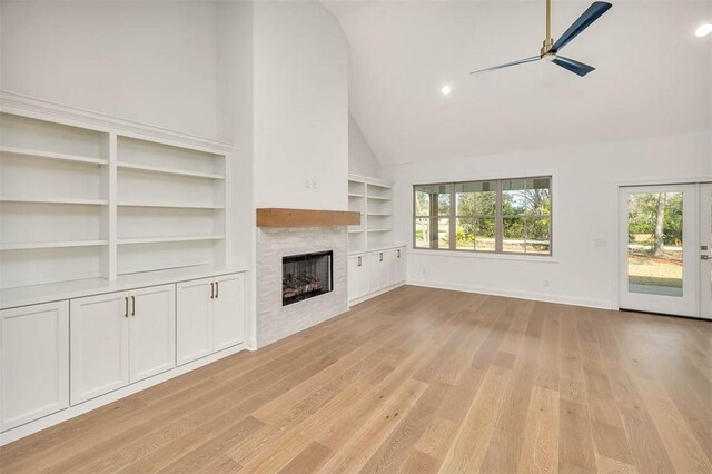 unfurnished living room with ceiling fan, a fireplace, built in features, and light wood-type flooring