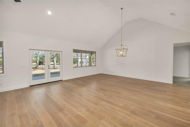 unfurnished living room featuring french doors, high vaulted ceiling, a chandelier, and light hardwood / wood-style floors