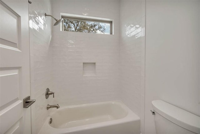 bathroom with tiled shower / bath combo and toilet