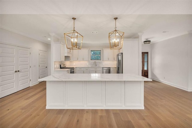 kitchen featuring a center island, hanging light fixtures, ornamental molding, appliances with stainless steel finishes, and white cabinets