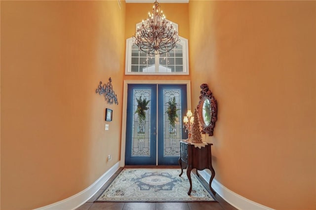 foyer featuring baseboards, a notable chandelier, and tile patterned flooring