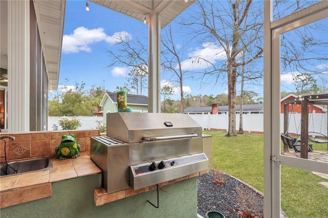 view of patio featuring a sink, area for grilling, a fenced backyard, and exterior kitchen