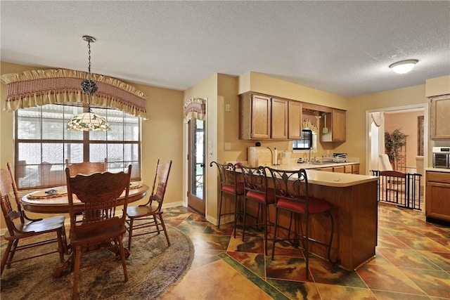 300 Bushoan Rd, Brunswick, GA 31525 - kitchen with a textured ceiling, a peninsula, light countertops, a kitchen breakfast bar, and baseboards